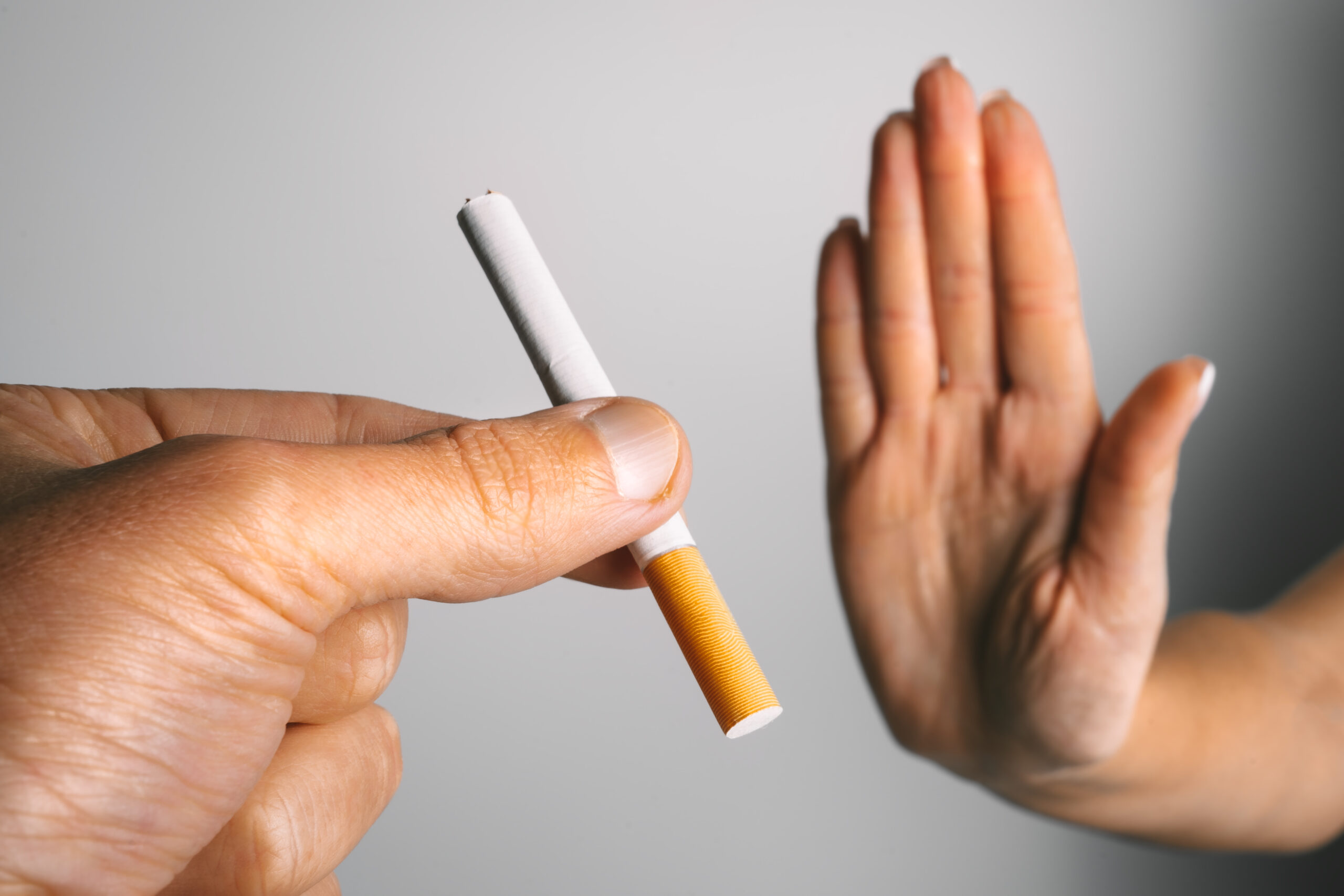 Woman showing stop sign with hand and refusing to take cigarette. No smoking or quit smoking concept. High quality photo